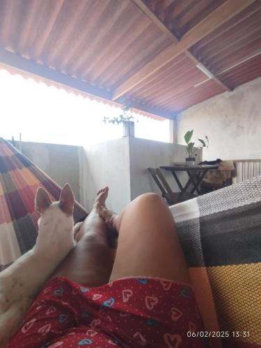 a woman laying on a hammock with a dog at PV house in Rio das Ostras
