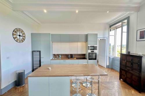 une cuisine avec une table et une horloge au mur dans l'établissement Appartement de 160m2 proche centre Lyon, à Caluire-et-Cuire