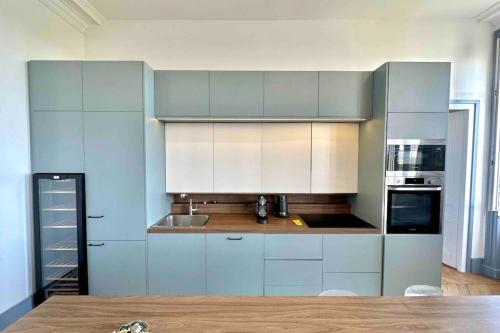 une cuisine avec des armoires et des appareils bleus et blancs dans l'établissement Appartement de 160m2 proche centre Lyon, à Caluire-et-Cuire