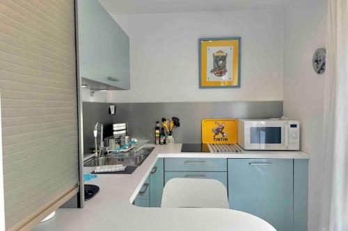- une cuisine avec des placards bleus et un four micro-ondes dans l'établissement Cosy studio Lyon 1er Croix Rousse, à Lyon