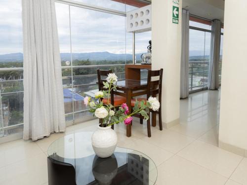 a dining room with a vase with flowers on a glass table at Hotel San Marino Tarapoto in Tarapoto