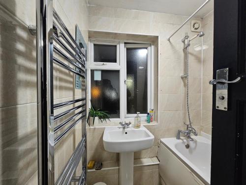 a bathroom with a sink and a toilet and a window at Rooms Near Canary wharf in London