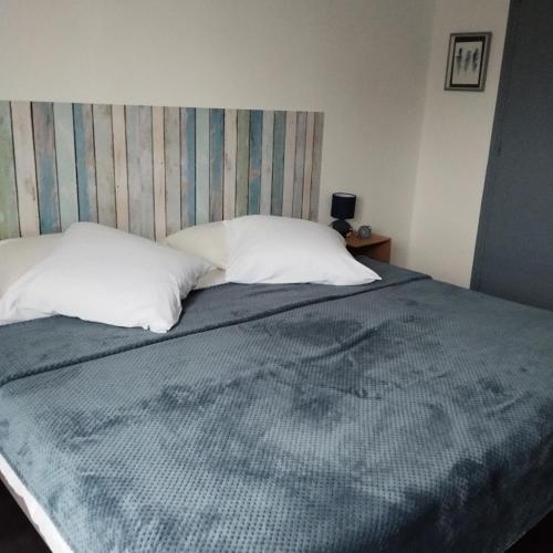 - un lit avec 2 oreillers blancs et une couverture bleue dans l'établissement F2 La Corniche 