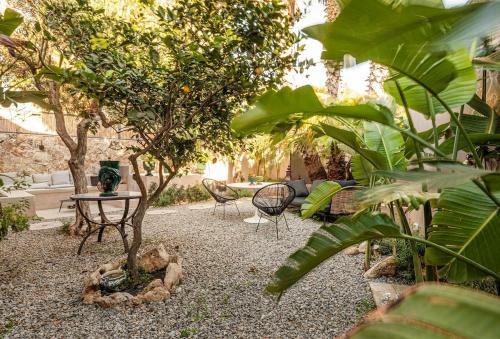 a garden with a table and chairs and trees at Dèpendance Armonia - 100 meters walk from the beach in Donnalucata