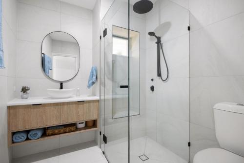 a bathroom with a shower and a sink and a mirror at 1-5 Petrel Street Peregian Beach QLD 4573 in Peregian Beach