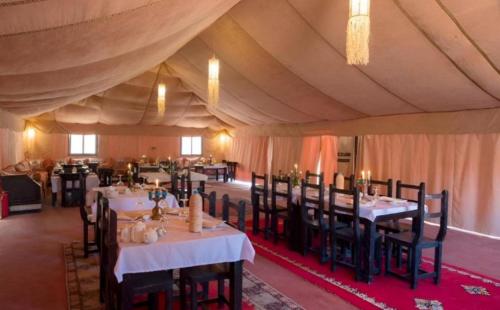 a dining room with tables and chairs in a tent at Private Luxury Camp in Merzouga