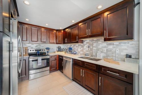 a kitchen with wooden cabinets and stainless steel appliances at Luxury Oceanfront Condo with Private Beach Access in Oceanside