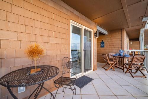 a patio with a table and chairs and a balcony at Luxury Oceanfront Condo with Private Beach Access in Oceanside