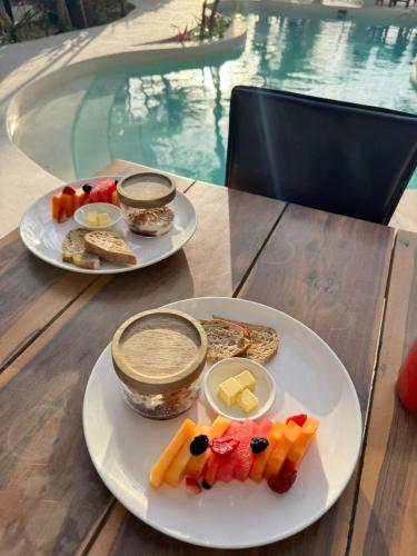 two plates of food on a table next to a pool at Garden Studio at Soliman Bay in Balcheil