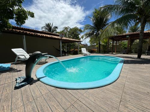 a dolphin shaped swimming pool with a dolphin fountain at Chácara Lara Bela in Praia do Saco