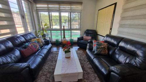 a living room with leather couches and a coffee table at Baguio Brentwood Villas in Baguio