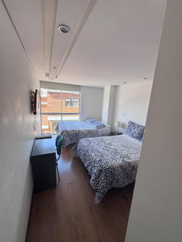 two beds in a small room with a window at Hotel link in Chiquinquirá