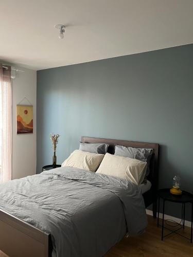 une chambre avec un grand lit avec un mur bleu dans l'établissement Cozy Flat in Saint Ouen, à Saint-Ouen