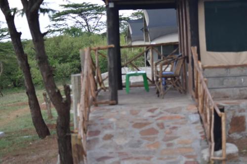 a porch of a house with a table and a chair at Orboma Masai homestay in Sekenani