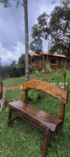 a wooden bench sitting in the grass next to a tree at Recanto do Leão in Alagoa