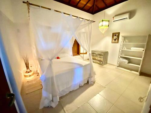 une chambre avec un lit blanc dans une pièce dans l'établissement Casa Exclusiva na Falésia - Barraca da Maré, Arraial d'Ajuda, à Arraial d'Ajuda