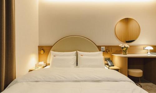 a bedroom with a large white bed with a mirror at Hound Hotel chuncheon in Chuncheon