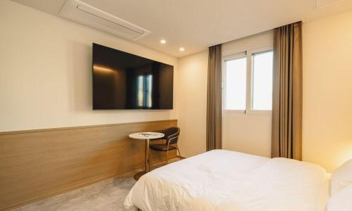 a bedroom with a bed and a table and a tv at Hound Hotel chuncheon in Chuncheon