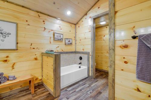 a log cabin bathroom with a tub and wooden walls at Hot Tub, Fireplace and Views Sevierville Retreat! in Sevierville