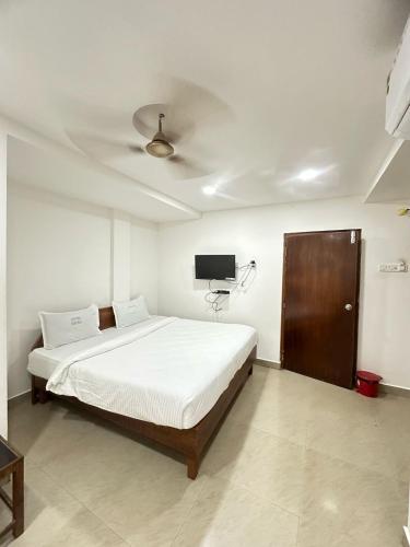 a bedroom with a bed and a flat screen tv at Hotel Safra in Chennai