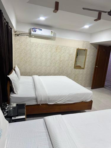 a hotel room with two beds and a air conditioner at Hotel Safra in Chennai