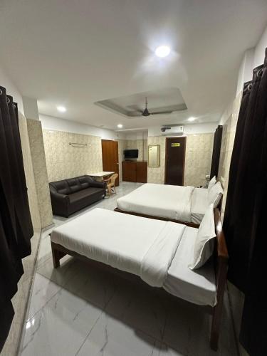 a hotel room with two beds and a couch at Hotel Safra in Chennai