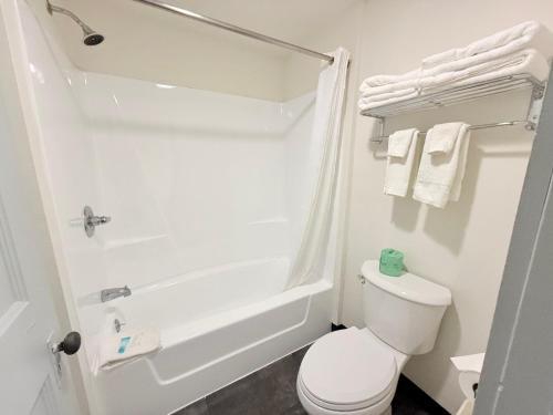 a white bathroom with a toilet and a bath tub at Don Q Inn in Dodgeville