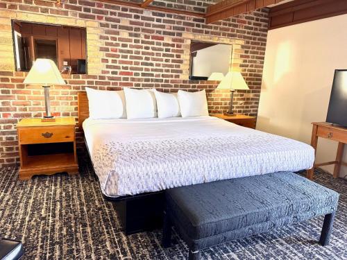 a bedroom with a large bed and a brick wall at Don Q Inn in Dodgeville