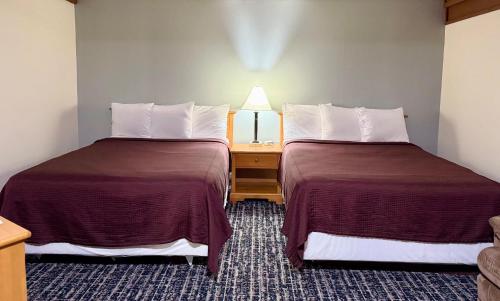 a hotel room with two beds and a night stand at Don Q Inn in Dodgeville