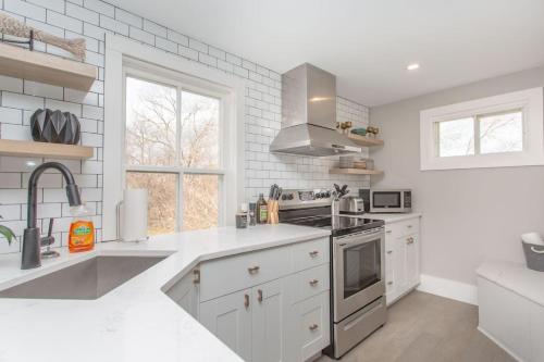 a white kitchen with a sink and a stove at Boutique Quality Home Downtown by the Shaw in Niagara on the Lake