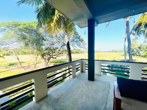 a balcony with a view of the ocean and palm trees at Tranquil Sanctuary Yala in Tissamaharama