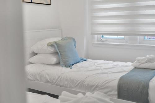 a white bedroom with a bed with pillows and a window at Fire and Fun Luxe Stay w Pool Hot Tub and Game Room in Linden
