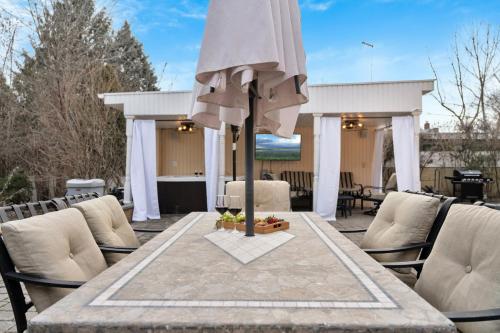 a table with an umbrella on a patio at Fire and Fun Luxe Stay w Pool Hot Tub and Game Room in Linden