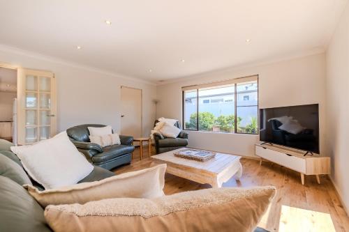 a living room with a couch and a tv at Morning Light Beach House - by the BnB Collection in Albany