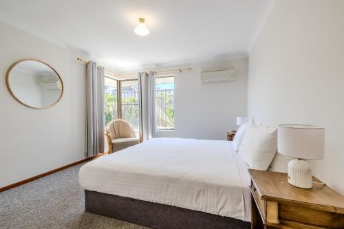 a bedroom with a large bed and a mirror at Morning Light Beach House - by the BnB Collection in Albany