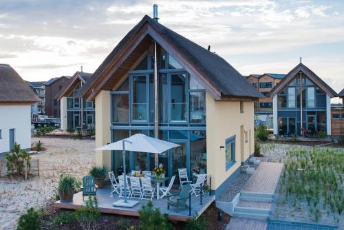 ein Haus mit einem Wintergarten mit einem Tisch und Stühlen in der Unterkunft Ostsee - Reetdachhaus Nr 42 "Waterkant" im Strand Resort in Heiligenhafen