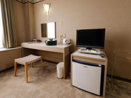 a hotel room with a tv and a desk with a tvictericter at Sagayamato Onsen Hotel Amandi in Saga