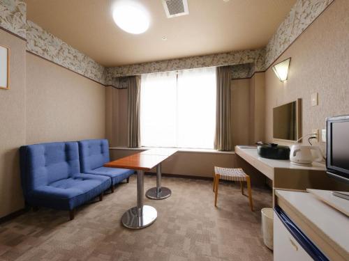 a room with a blue chair and a table and a television at Sagayamato Onsen Hotel Amandi in Saga