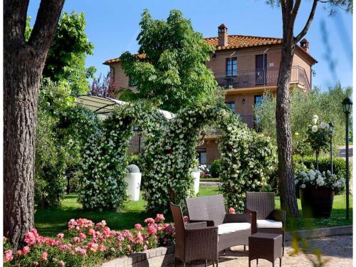 a garden with chairs and flowers in front of a building at tolles Apartment in einer Residence in der Toskana in Petrignano sul Lago
