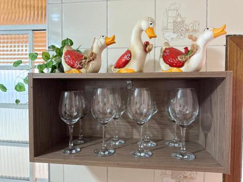 ein Holzregal mit Weingläsern und Vögeln darauf in der Unterkunft Solar Campos do Jordão - Perfeita para casal e Família in Campos do Jordão