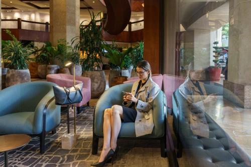 a woman sitting in a chair looking at her cell phone at Intercontinental Real Guatemala by IHG in Guatemala