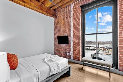 1 dormitorio con pared de ladrillo, cama y ventana en Stunning 5 Star Stay! Guest Favorite with River View, en Saint Louis