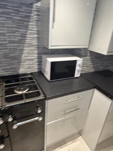 a kitchen with a microwave and a stove at Cosy room 6 en-suite in Ifield