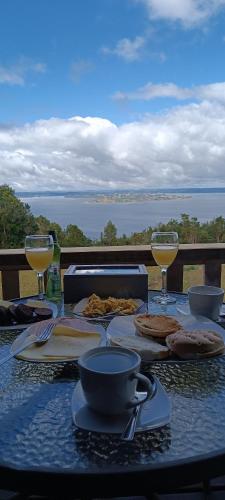 a table with glasses of wine and food on it at Cabañas Chillwe in Coñao