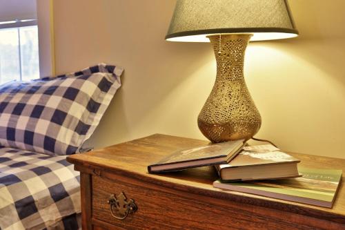 a lamp on a table next to a bed with books at Chittenden Farmhouse - Historic 4BR, 2BA, 20 Min to Skiing, 7 Min to Mountaintop Resort in Chittenden