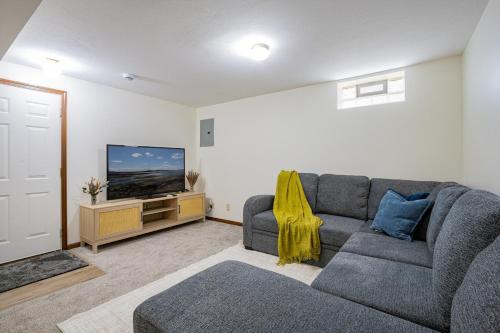 a living room with a gray couch and a flat screen tv at Comfort Awaits at Cozy Get Away - Dog Friendly in Akron