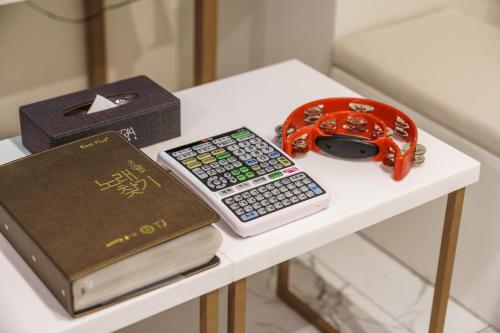 a table with a book a remote control and a calculator at Hotel MARIA in Pyeongtaek