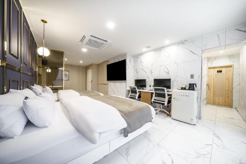 a white bedroom with a bed and a desk at Hotel MARIA in Pyeongtaek