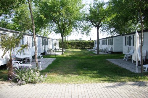 a group of camping cottages with chairs and trees at Camping Klaus in Cavallino-Treporti
