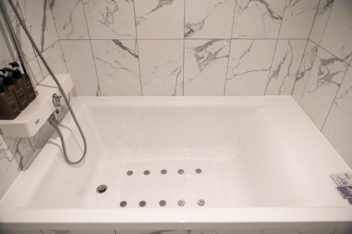 a white bath tub in a bathroom with marble walls at Hotel MARIA in Pyeongtaek